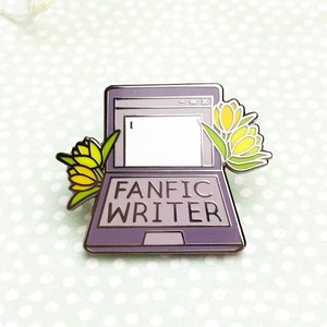 May include: Purple enamel pin of a laptop with the text "Fanfic Writer" and yellow flowers on the side.