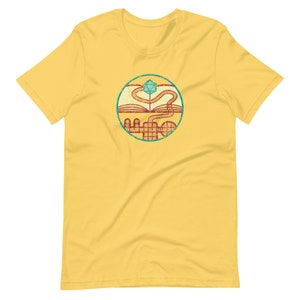 May include: Yellow t-shirt with a vintage-style graphic of a book, a winding path, and a blue and green twenty-sided die.