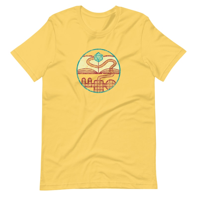 May include: Yellow t-shirt with a vintage-style graphic of a book, a winding path, and a blue and green twenty-sided die.