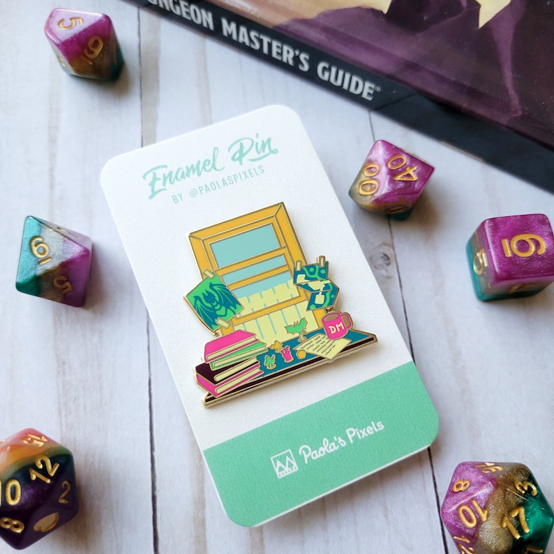 K&ouml;nnte beinhalten: Emaille-Anstecknadel mit einer farbenfrohen Illustration einer Tischszene mit B&uuml;chern, einer Tasse und einem Fenster. Die Anstecknadel befindet sich auf einem gr&uuml;nen Hintergrund mit dem Text "Enamel Pin by @PaolosPixels" und "Paola's Pixels".