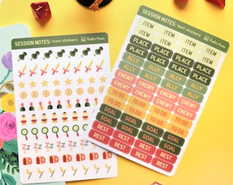 May include: Two sheets of sticker paper with colourful icons and text. The top sheet has icons for swords, stars, coins, potions, magnifying glasses, chests, and wands. The bottom sheet has text stickers that say "Item", "Place", "Ally", "Enemy", "To Do", "Goal", and "Rest".
