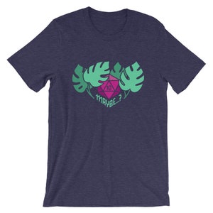 Puede incluir: Una camiseta azul marino con un gr&aacute;fico rosa y verde de un dado de diez caras rodeado de hojas. El texto "MAYBE...?" est&aacute; debajo del dado.