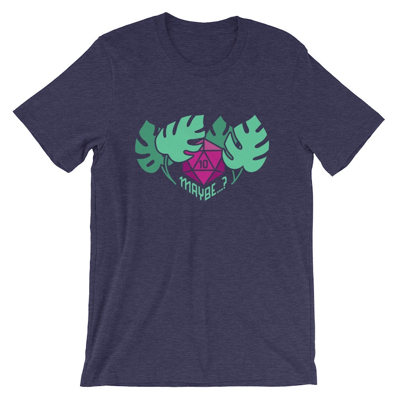 Puede incluir: Una camiseta azul marino con un gr&aacute;fico rosa y verde de un dado de diez caras rodeado de hojas. El texto "MAYBE...?" est&aacute; debajo del dado.