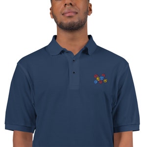 May include: A navy blue polo shirt with a small embroidered design of colorful dice.