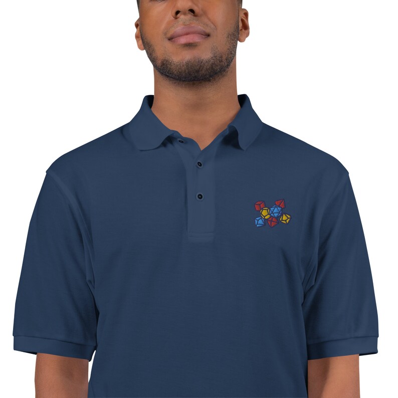 May include: A navy blue polo shirt with a small embroidered design of colorful dice.