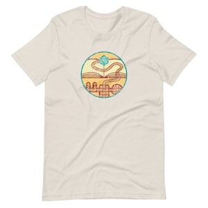 May include: A beige t-shirt with a vintage-style circular graphic. The graphic features a stylized book with a winding path leading to a blue and green dice.