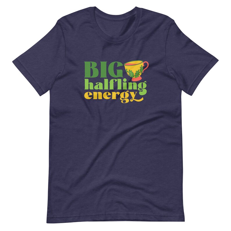 May include: A navy blue t-shirt with the text "BIG halfling energy" in green and yellow lettering. A small yellow teacup with green leaves is above the text.