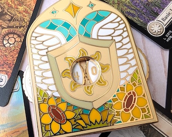 May include: A gold-toned metal enamel pin shaped like an arched window, featuring white wings, yellow sunflowers, and a central shield with a sun emblem. A circular cutout in the center displays the numbers 4 and 0 on a rotating inner dial.