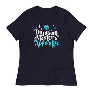 May include: A navy blue t-shirt with a white design that says "Dungeon Master's Apprentice" with a blue 20-sided die and stars.