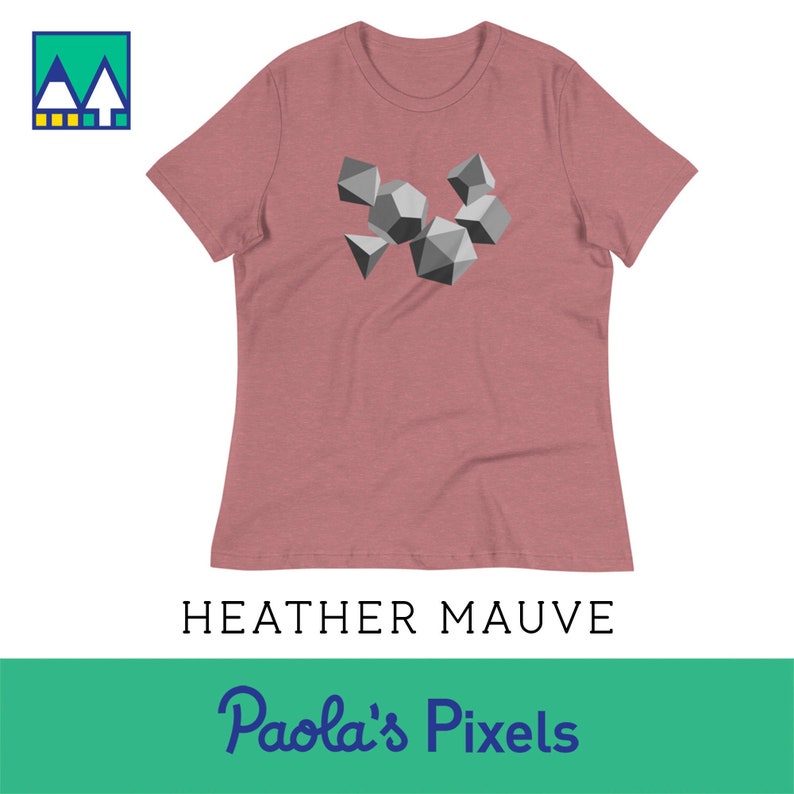 May include: Heather mauve women's t-shirt with a graphic of geometric shapes in shades of gray. The text "Paola's Pixels" is printed in blue on a green background below the image.