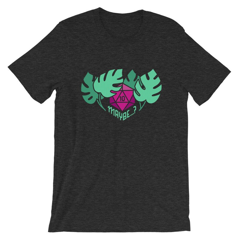 Puede incluir: Camiseta gris oscuro jaspeada con un dado rosa y verde con el n&uacute;mero 10 visible. El dado est&aacute; rodeado de hojas verdes de monstera y el texto "MAYBE...?" est&aacute; debajo del dado.