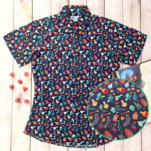 Puede incluir: Una camisa de botones de manga corta de color azul marino con un estampado colorido de frascos de pociones, hierbas y otros objetos m&aacute;gicos. La camisa tiene un cuello abotonado y un corte holgado.