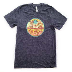 May include: A dark heather grey t-shirt with a vintage-style graphic of a book, a dice, and a winding path. The graphic is in shades of yellow, orange, red, and blue.