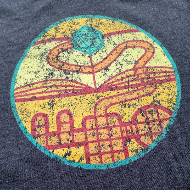 May include: A distressed, circular design with a turquoise blue, geometric shape at the top. The design features a yellow, orange, and red maze-like pattern with a black grid in the center.
