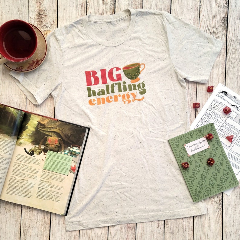 May include: A white t-shirt with a green, orange, and red graphic that says "BIG halfling energy" and a cartoon image of a teacup.