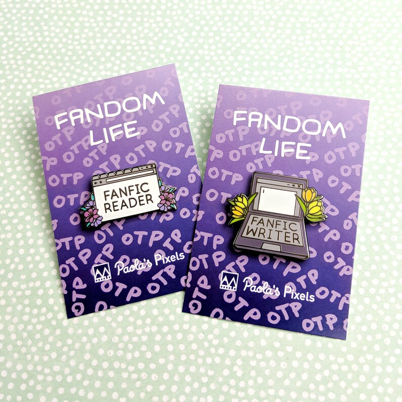 May include: Two enamel pins with a purple and blue gradient background. The pins feature a laptop with the text "Fandom Life" and a browser window with the text "Fanfic Reader" or "Fanfic Writer". The pins are surrounded by small flowers.