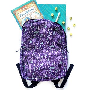 May include: Purple backpack with a whimsical pattern of swords, potions, dice, and other fantasy-themed illustrations. The backpack is lying on a white surface with a book and dice scattered around it.