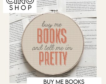 May include: A cross-stitch pattern in a wooden hoop with the text "buy me BOOKS and tell me I'm PRETTY" in coral letters. The design is on a beige fabric, surrounded by pages of a book. The words "BUY ME BOOKS CROSS STITCH PATTERN" are at the bottom.