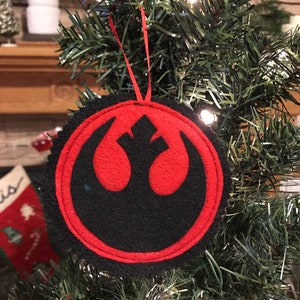 May include: A red and black felt Christmas ornament featuring the Rebel Alliance symbol from Star Wars.