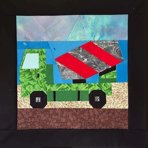 May include: A colorful patchwork quilt square featuring a green cement truck with black wheels and a red and gray mixer. The background includes blue and light blue sky elements, and brown and tan ground. The truck has a light blue window.