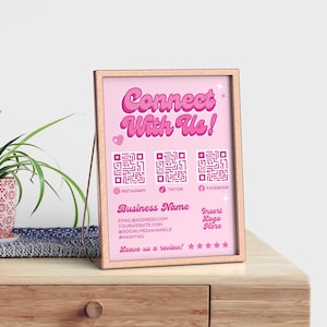 以下が含まれることがあります： ピンクと白のサインに「Connect With Us!」の文字と、Instagram、TikTok、FacebookのQRコードが書かれています。サインには、「Business Name」、メールアドレス、ウェブサイトアドレス、ソーシャルメディアハンドル、ハッシュタグ、そして「Leave us a review!」の文字と5つの星も書かれています。