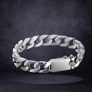 Peut inclure: Un bracelet chaîne gourmette argenté brillant. Il est composé d'une série de maillons arrondis et imbriqués, et d'un fermoir rectangulaire. Le fermoir est de conception simple. Le bracelet est en métal.