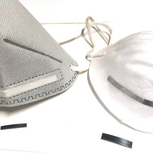 May include: Two white face masks, one with a grey fabric and a nose wire, the other with a white fabric and a metal nose wire.