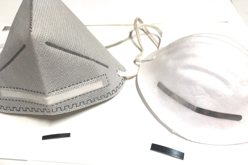 May include: Two white face masks, one with a grey fabric and a nose wire, the other with a white fabric and a metal nose wire.