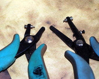 May include: Two metal hole punch tools with blue handles. The tool on the left has a silver punch and the tool on the right has a black punch.