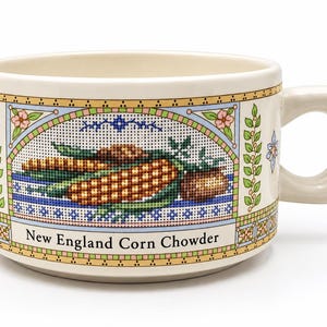 May include: A cream-colored ceramic soup mug featuring a cross-stitch style graphic of corn cobs and potatoes. The text "New England Corn Chowder" is printed in black on the front, surrounded by a decorative border of flowers and geometric patterns.