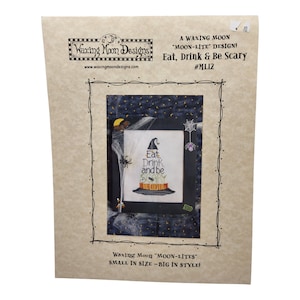 May include: A cross-stitch pattern kit titled Eat, Drink & Be Scary by Waxing Moon Designs. The packaging features a central image of a witch hat design with a spider web, a spider, and the text Eat, Drink and be SCARY on a dark background.