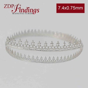 May include: Silver-toned metal crown-shaped jewelry finding with a delicate, intricate design. The finding measures 7.4 x 0.75 mm.