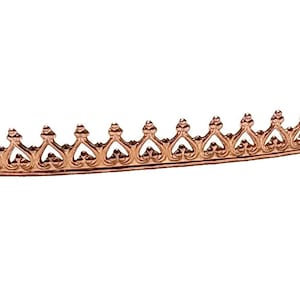 May include: A rose gold crown trim with a delicate, intricate design. The trim is made of metal and has a shiny finish.