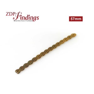 May include: A gold-colored metal chain link measuring 57 mm in length. The chain is twisted and has a flat, oval-shaped link.