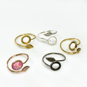 May include: Five adjustable rings with a leaf design. The rings are made of gold, silver, and rose gold metal. Some rings have a clear stone, while others have a pink stone.