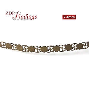 Op de afbeelding: Een goudkleurige metalen trim met een decoratief bloemmotief. De trim is 7,4 mm breed.