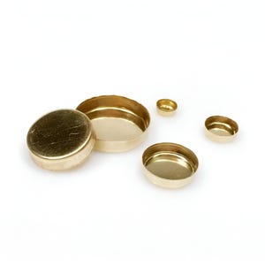 May include: Four gold-colored metal lids of different sizes. The lids are round and have a smooth, shiny finish.