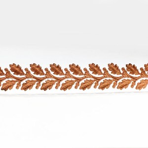 May include: A copper-colored trim with a repeating pattern of oak leaves. The trim is on a white background.