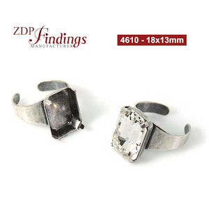 May include: Two adjustable silver-tone rings, one with an empty rectangular setting and the other with a large, clear rectangular crystal. The rings are labelled "4610 - 18x13mm" and are from "ZDP Findings Manufacturer".