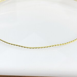 May include: A thin gold twisted wire bangle bracelet.