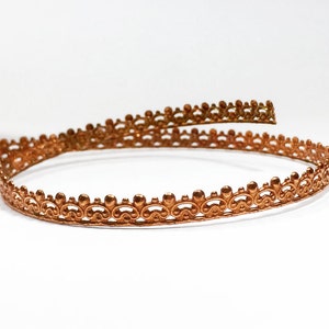 May include: A coiled copper trim with a decorative scalloped edge.