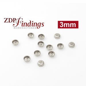 May include: A collection of 12 silver-colored, 3mm round metal cup-shaped findings. The findings are arranged on a white surface. The text "ZDP Findings Manufacturer" and "3mm" are visible in the image.