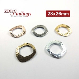 Könnte beinhalten: Fünf gehämmerte Metallringe in verschiedenen Ausführungen: Gold, Silber, Roségold, Messing und Antik-Silber. Jeder Ring misst 28 x 26 mm und hat eine quadratische Form mit abgerundeten Ecken.