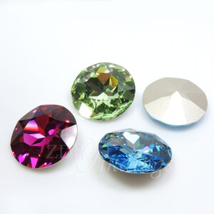 May include: Four faceted gemstones in shades of red-violet, green, blue, and silver. The gemstones are oval and round, with multiple facets to reflect light. The gems are set against a white background.