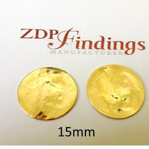 Op de afbeelding: Twee gouden metalen cirkels met een gehamerde textuur en een gat in het midden. De cirkels hebben een diameter van 15 mm. ZDP Findings Manufacturer.