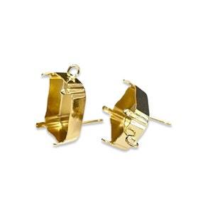 May include: Two gold-toned metal settings for setting stones. Each setting has a loop at the top and a pin on the bottom.