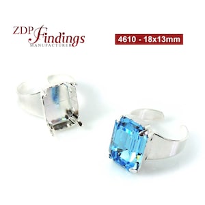 May include: Two silver-coloured adjustable rings. One ring is empty, and the other features a large, rectangular, light blue gemstone. The text "4610 - 18x13mm" is in the upper right corner. The rings are on a white background.