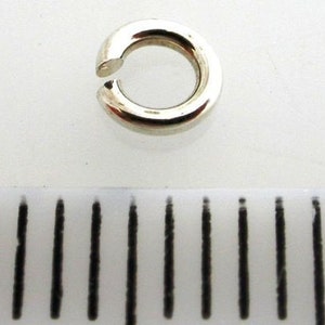 May include: Silver jump ring, a small circular metal ring used for connecting jewelry components.