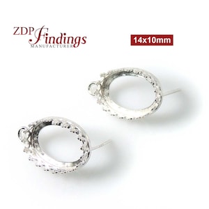 Könnte beinhalten: Zwei silberne ovale Ohrringfassungen mit einem dekorativen Rand. Die Fassungen sind 14 mm x 10 mm groß.
