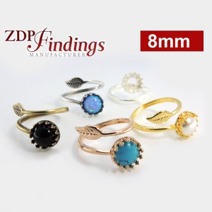Puede incluir: Cinco anillos ajustables con un diseño de hoja y un engaste de 8 mm. Los anillos se muestran con piedras de diferentes colores, incluyendo negro, blanco, turquesa, ópalo y un engaste en blanco.